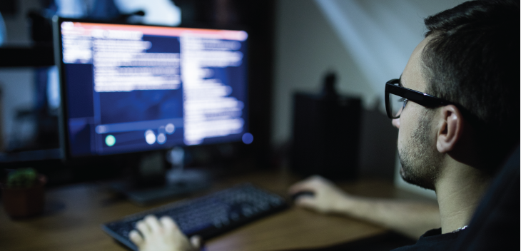 Man on computer in dark light room