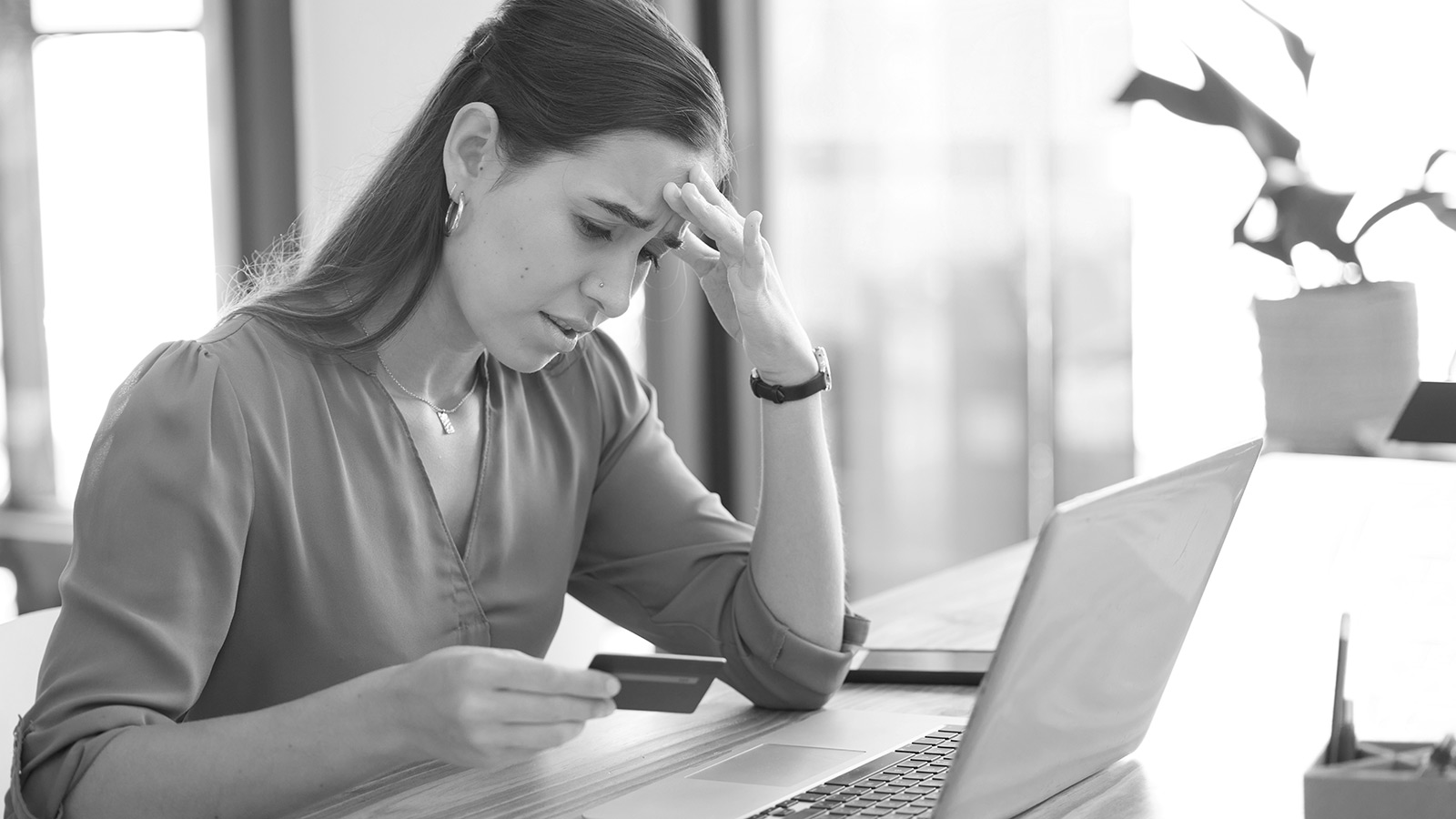 Woman with hand on forehead looking at laptop